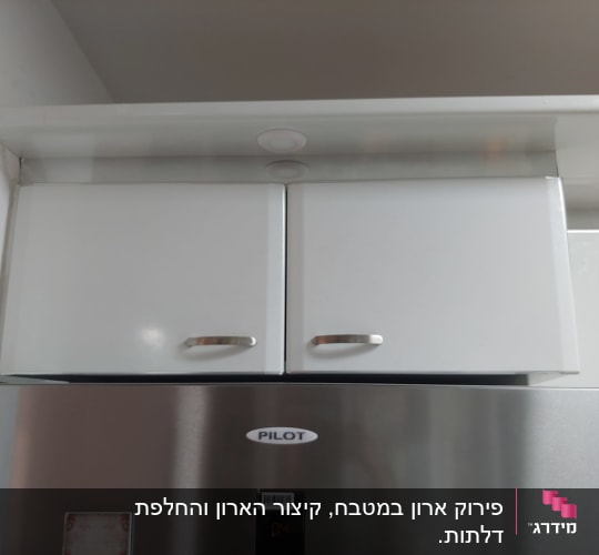ארון מטבח לבן עם ידיות מתכת מעל מקרר